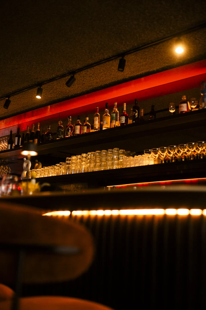 Verlichte flessenrekken achter de bar van Alba